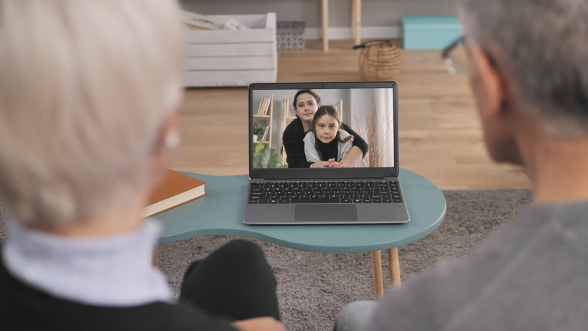 family video chat,back view of grandparents talking to grandchildren using computer conference app,social distancing elderly couple use technology to communicate with grandkids Royalty-Free Stock Footage #1065569299