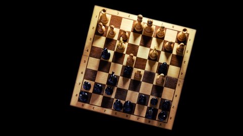Old chess board with figures from the Soviet Union era on a black background, top view time lapse. Chess opening Queen Gambit, timelapse
