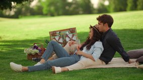 Young people chilling on blanket on green lawn at summer park. Smiling couple having rest on picnic on green meadow. Young man and woman laughing outdoors - Powered by Shutterstock - Get 15% off with code: PIKWIZARD15