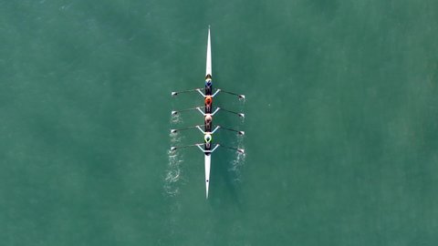 Sport Canoe with a team of four people rowing on tranquil water, Aerial view.