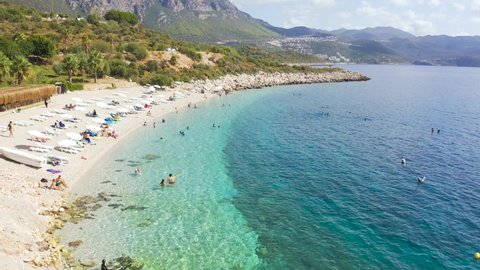 Aerial view azure sea and swiming people on the white sand beach on high mountains background in Kas, Antalya, Turkey. Aerial view 4K.