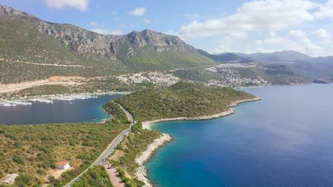 The road runs along the coast peninsula Kas town on gorgeous setting a beautiful cove, charming nature and mountains in Antalya, Turkey. Aerial view 4K.