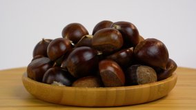 Rotating chestnuts isolated  on white background. High quality 4k footage. Rotating nuts in a wooden bowl. Studio light.  Product for sale.  Looping video. Copy space.
