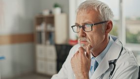 Experienced Middle Aged Male Doctor Wearing White Coat Working on Personal Computer at His Office. Senior Medical Health Care Professional Working with Test Results, Patient Treatment Planning. - Powered by Shutterstock - Get 15% off with code: PIKWIZARD15