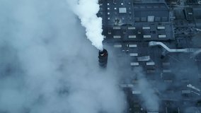 Large factory with white steam and smoke coming from chimneys and smokestacks. 4K aerial footage.