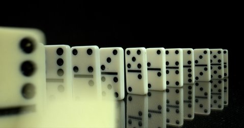 Dominoes on black glossy reflective surface. Chain reaction. The Domino Principle. Board game. Falling dominoes. High quality.