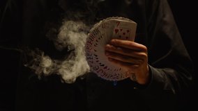 Close-up of a Magician Hand Performing Card Trick . Burning card on black Background with smoke . Card Mechanic holding flaming card in hand . Shot on ARRI Alexa cinema camera in Slow Motion 