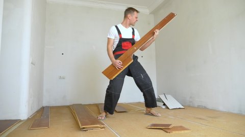 a man builder in overalls is resting and lounging around, pretending to play the guitar on a laminate board