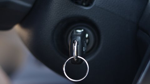 Man inserts the ignition key and starts the car.