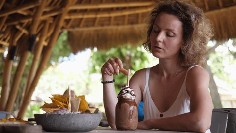 Caucasian girl having lunch alone in a beach restaurant, looks behind her shoulder. Travelling solo concept
