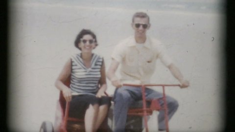 MIAMI, FLORIDA, JULY, 1960: A couple rides a special beach motorcycle with a side cart while on their Florida honeymoon in 1960.