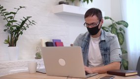 Young caucasian man stay home working from home wearing protective mask using laptop and internet. Cozy Home office, workplace coronavirus pandemic, covid 19 quarantine. Remote work,freelancer - Powered by Shutterstock - Get 15% off with code: PIKWIZARD15
