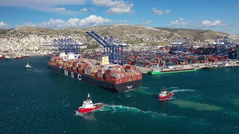 Perama, Attica - Greece - January 13 2021: Aerial drone video of industrial container cargo vessel MSC Zoe approaching logistics unloading import and export container terminal of Perama - Piraeus