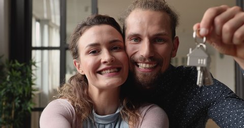 Cheery couple celebrate moving to new rented, bought house, laugh kiss each other show bunch of keys at camera, close up. Happy homeowners portrait, relocation day, bank loan for young family concept