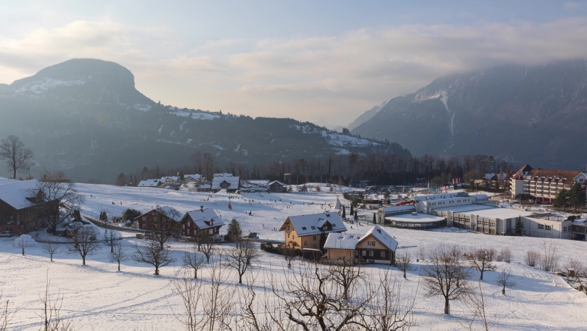 Timelapse of people sledging in the Swiss Alps. Mountains covered with snow. Morschach, Canton Schwyz, Switzerland.