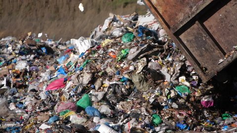 A dump truck unloads a pile of garbage at a landfill in slow motion. Dump of unsorted waste.