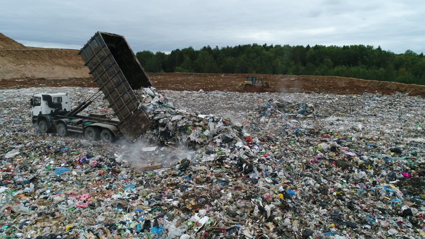 Aerial view. A dump truck unloads a pile of garbage at a landfill. Dump of unsorted waste. Drone shot of working trash management. Royalty-Free Stock Footage #1065645244