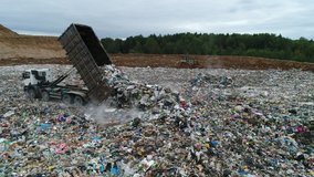 Aerial view. A dump truck unloads a pile of garbage at a landfill. Dump of unsorted waste. Drone shot of working trash management. - Powered by Shutterstock - Get 15% off with code: PIKWIZARD15