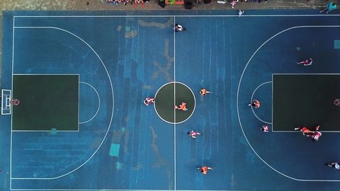 Top view of basketball court during the game outdoors. Players are on the court, poplar fluff falls on the court, resembling snow