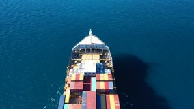 Aerial drone flight video over industrial colourful tanker carrying heavy truck size containers cruising the Aegean deep blue sea