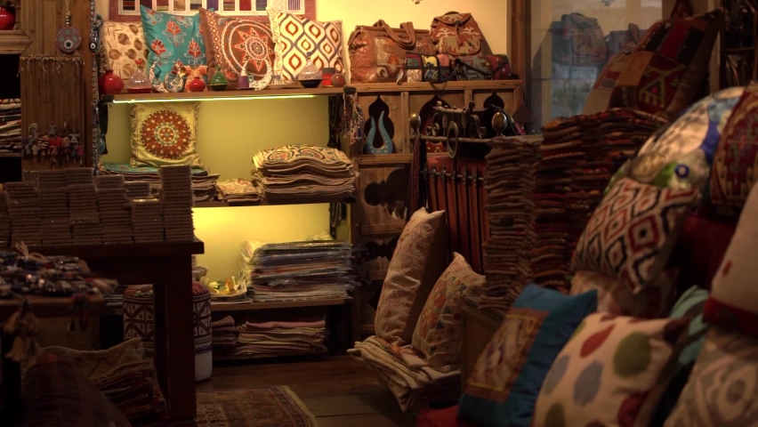 Elegant colorful traditional Turkish handmade pillows and souvenirs with patterns in empty store of stylish ethnic items at market.