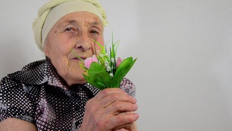 Happy grandmother with flowers on women's day. Mothers Day. Congratulations concept. March 8. Old grandmother with delicate flowers close-up. Smiling mother accepts congratulations. Grandmother 