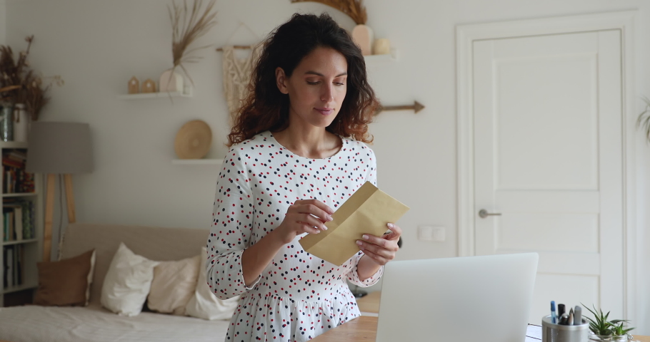 Happy attractive young woman opening paper envelope, reading pleasant news in letter postal correspondence, feeling excited of getting event invitation or university admission post notification. | Shutterstock HD Video #1065667285
