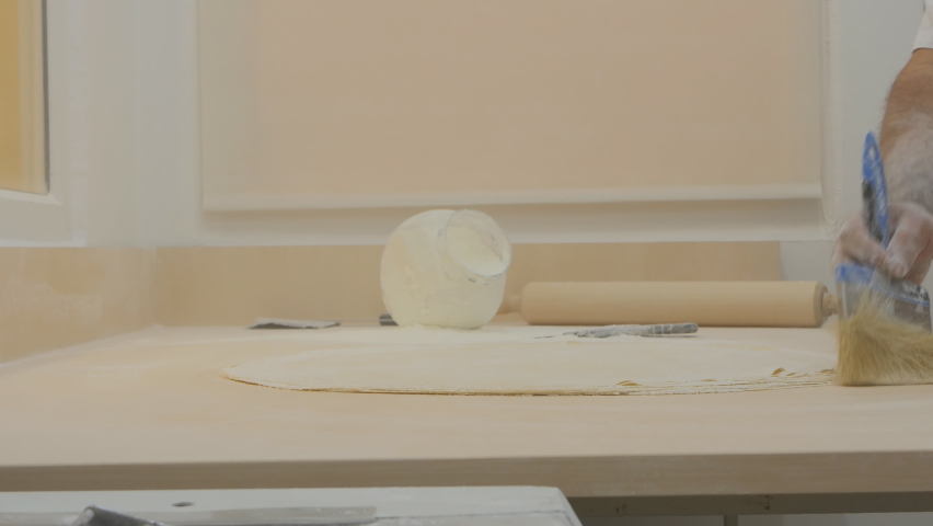 Confectioner baker turkish man making baklava dough. He brushes the flour aside and flattens the dough with his palms. Making real Turkish baklava | Shutterstock HD Video #1065668197