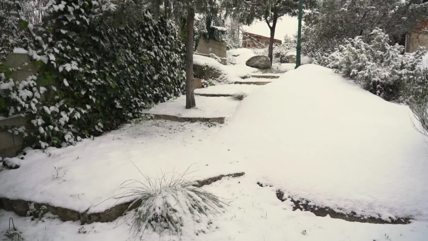 Stone stairs in a small garden covered in white snow and obscuring the steps