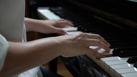 Young woman playing piano, learning to play piano, taking piano lessons