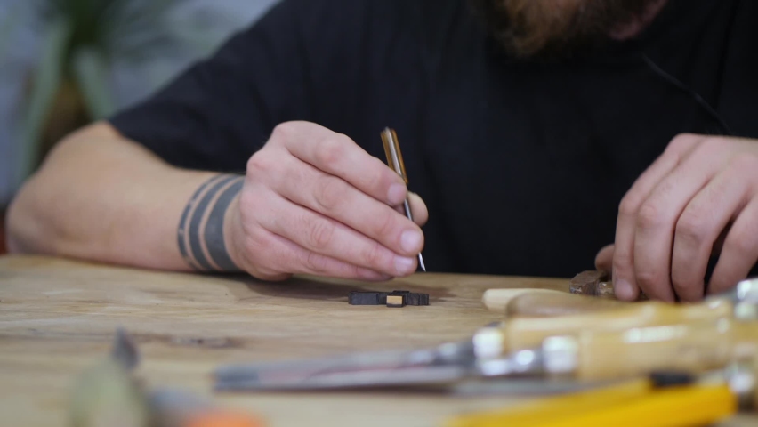 A woodcarver carves an Orthodox cross from ebony with a chisel and hammer. a master carves a wooden cross