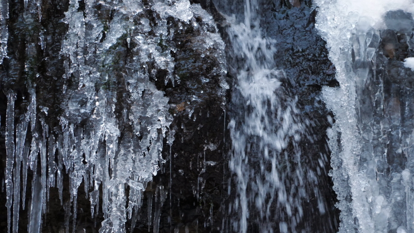 Water flowing down the surface of the rock is frozen in the cold of winter. Waterfalls and water drops. Beautiful nature freezing