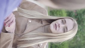 Vertical video of a young skinny girl in the park. Girl talking with someone