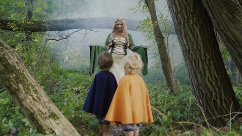 Scene of meeting elf woman and little hobbits or gnome toddler boys in green forest. Cosplay, halloween, fairy tale characters concept.