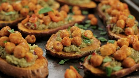 Man Hand pick Sweet potato toast loaded with avocado guacamole and baked chickpeas.