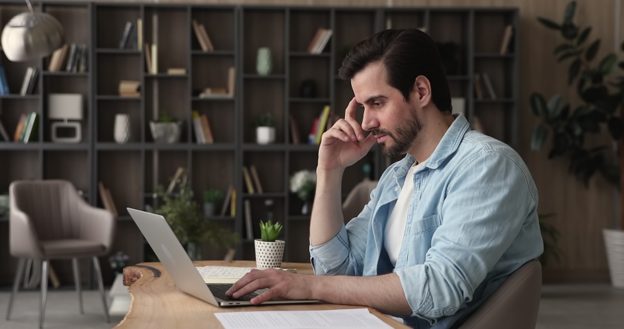 Serious thoughtful businessman office employee sit at desk texting on laptop, check corporate e-mail, writing answer, corresponding with client, working solve issues remotely use internet and computer Royalty-Free Stock Footage #1065694537