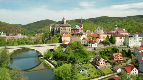 Flight over Loket castle, surrounded by river Ohri and small houses on a river shore, near Kariovy Vary, Czech Republic.