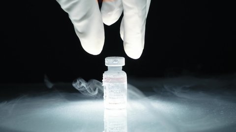 Researcher's hand pick up frozen cold Vaccine vial for Covid-19 with mRNA technology stored in subzero low temperature -70 celsius. Effective thermal controlled for global distribution conditions.