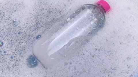 Bottles of detergents float in the foam. The concept of the dangers of household chemicals. Sodium laureate, parabens, sulfates and other hazardous chemical compounds in the foam.  