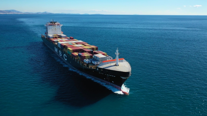 Saronic gulf, Attica - Greece - January 14 2021: Aerial drone video of MSC truck size container cargo vessel cruising in deep blue sea near commercial port of Piraeus
