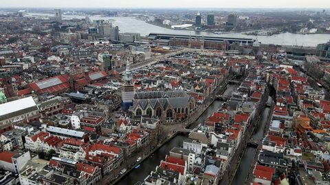 The Oude Kerk in Amsterdam city center on the red light district aerial drone view central station in the background
