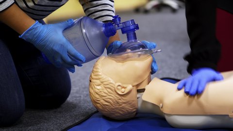 Training course on a manikin. Practitioners giving breath exercises on a dummy at resuscitation. Compression during heart attack on a mannequin.