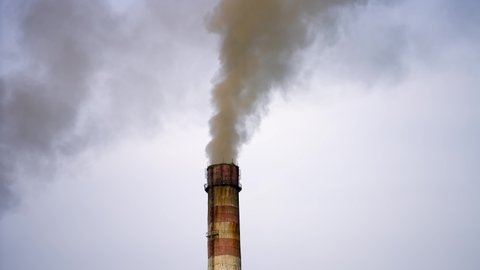 Smokestack exhausting combustion gases into the air. Dense smoke from pipes pollute the atmosphere. Dangerous emissions in the sky. Climate change.