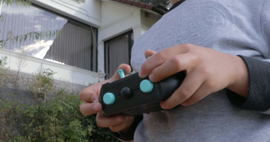 Kid boy playing and operating with radio controlled toy outdoor