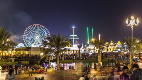 Main square and lake in Global Village with crowd and attractions timelapse in Dubai, UAE. Brightly colouredl lights and highly detailed pavilion facades have helped make Global Village one of Dubai's