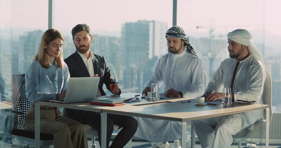 Two arabian entrepreneurs investing in business signing up documents for construction contract. Multi-ethnic happy business people applauding for successful deal.
