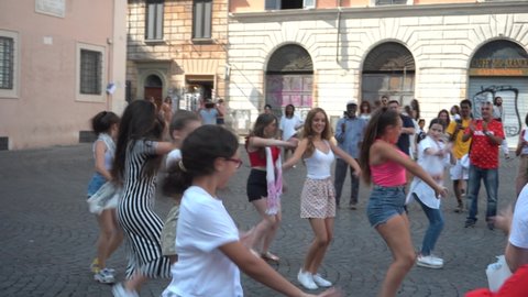 Rome, Italy - July 14, 2019: Group of girls perform a dance in the street on the square in front of the church of Santa Maria in Trastevere on a summer day