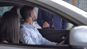 Happy new car owners getting key from auto dealer while sitting in purchased automobile at dealership. Smiling young couple taking key to bought car and sealing deal with handshake in auto showroom - Powered by Shutterstock - Get 15% off with code: PIKWIZARD15