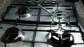 Pouring Milk İnto A Glass Coffee Pot On Top Of A Gray Gas Stove. Cinematic Shot