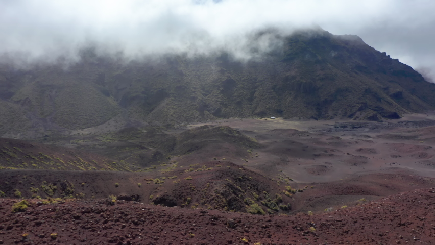 Aerial view of dark cooper and brown rocky hills and scenic mountain landscape on Hawaii island at sunrise, USA. Drone flying over old volcano crater at Haleakala National Park, nature background 4K